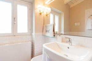 un bagno bianco con lavandino e specchio di Di punto in bianco home a Verona