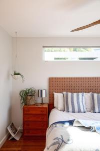 a bedroom with a bed with a wooden headboard and a window at Driftwood Rest Binalong Bay Sleeps 4 in Binalong Bay