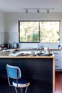 a kitchen with a blue chair and a counter at Driftwood Rest Binalong Bay Sleeps 4 in Binalong Bay