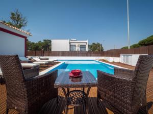 um pátio com uma mesa e cadeiras ao lado de uma piscina em Romã do Meco na Aldeia do Meco