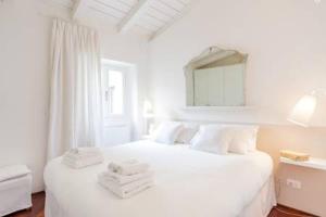 una camera da letto bianca con un letto e asciugamani di Di punto in bianco home a Verona