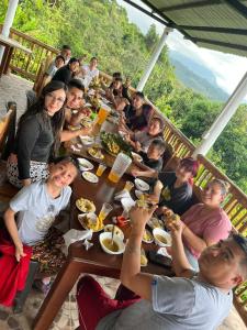 Eine Gruppe von Menschen, die an einem Tisch sitzen und Essen essen. in der Unterkunft Finca Agua Viva in Viotá