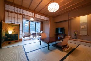 uma sala de estar com uma mesa e cadeiras e uma televisão em ふきや旅館 Fukiya Ryokan em Yugawara