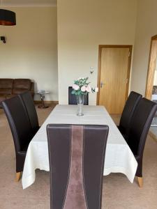 a table with chairs and a vase of flowers on it at Apartment 500 - Metro style apartment on NC500 in Thurso