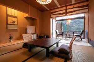 uma sala de estar com uma mesa e cadeiras e uma janela em ふきや旅館 Fukiya Ryokan em Yugawara