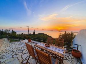 a wooden table and chairs on a patio with the sunset at Villa Ioanna in Kalamitsi