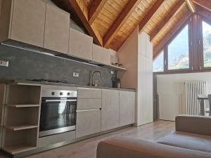 a kitchen with a stove top oven next to a couch at Appartamenti ALICE MOLVENO in Molveno
