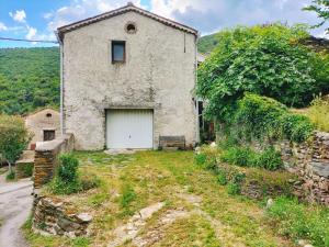 an old stone house with a white garage at Maison cooconing in Sumène