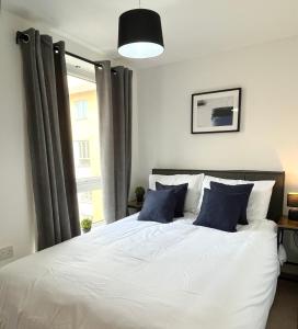 a bedroom with a large white bed with blue pillows at Beautiful Riverview Apartment Chelmsford in Chelmsford