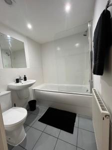 a white bathroom with a tub and a toilet and a sink at Beautiful Riverview Apartment Chelmsford in Chelmsford