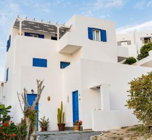 ein weißes Haus mit blauen Türen und Pflanzen in der Unterkunft Cozy little house in Ios in Chora, Ios