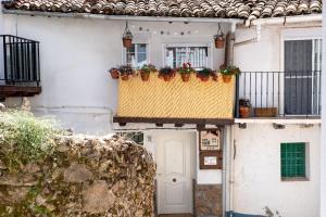 una casa blanca con flores en los balcones en Casa Rural El Burrito de Gredos en Pedro Bernardo