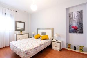 - une chambre avec un lit doté d'oreillers jaunes et d'un parapluie rouge dans l'établissement Cómodo apartamento en Almonte, à Almonte