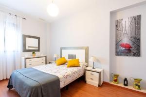 アルモンテにあるCómodo apartamento en Almonteのベッドルーム1室(黄色い枕と赤い傘付きのベッド1台付)