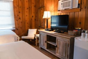 1 dormitorio con 1 cama y TV en un armario de madera en Whispering Winds Motel, en Auburn