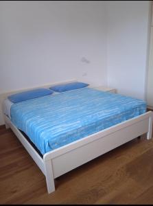 Una cama blanca con una manta azul encima. en Ca' Giorgio en Cavallino-Treporti