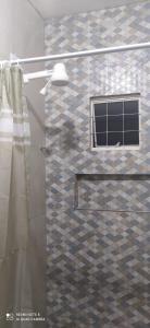 uma casa de banho com uma cabina de duche em vidro e uma janela. em Casa Confortável em Caruaru
