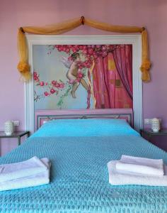 ein Schlafzimmer mit einem blauen Bett und einem Gemälde an der Wand in der Unterkunft Vive Mare in Sarandë