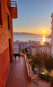 Eine Katze steht auf einem Balkon und sieht den Sonnenuntergang. in der Unterkunft Vive Mare in Sarandë