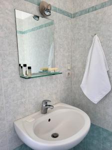 ein Badezimmer mit einem weißen Waschbecken und einem Spiegel in der Unterkunft Vive Mare in Sarandë