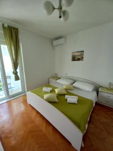 a bedroom with a large bed with a green blanket at SOBE ŠOTIĆ in Rab