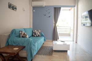 - un salon avec un canapé bleu et une fenêtre dans l'établissement Naiads Nest - The Blue Wave, à Varkiza