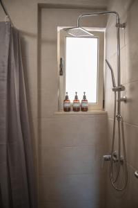 La salle de bains est pourvue d'une douche et d'une fenêtre. dans l'établissement Naiads Nest - The Blue Wave, à Varkiza