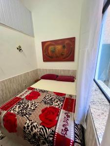 a small bedroom with a bed with a quilt on it at Pousada Diniz in Resende