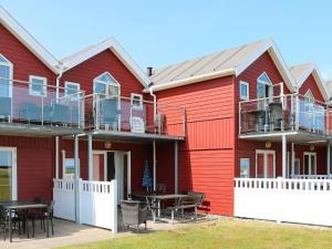 una casa roja con mesas y sillas delante en Holiday Home Havblik II, en Øster Hurup