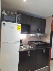 a kitchen with a white refrigerator and a sink at R.1105 Estudio Ejecutivo, céntrico y funcional. in Panama City +3 photos