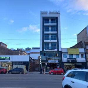 a tall building with cars parked in a parking lot at HOTEL PLAZA 6 in Sogamoso
