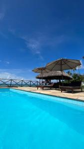 a large swimming pool with an umbrella and benches at Eco Paradise 110 - Cumbuco in Caucaia
