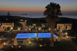 a resort with a pool and a palm tree at night at Fragoulis Village in Parasporos