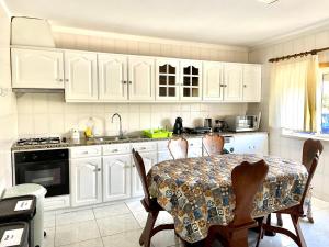 a kitchen with white cabinets and a table with chairs at Colina do Elétrico in Figueira da Foz