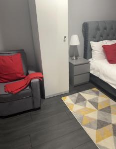 um quarto com uma cama, uma cadeira e um candeeiro em Mona's Home em Dagenham
