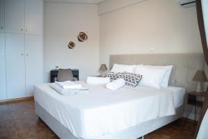 una camera da letto con un grande letto bianco con cuscini bianchi di Naiads Nest - The Cozy Retreat a Varkiza