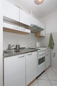 eine weiße Küche mit einer Spüle und einem Herd in der Unterkunft Apartments with a parking space Brsec, Opatija - 7755 in Brseč