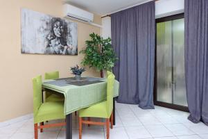 a dining room with a green table and chairs at Apartments with a parking space Brsec, Opatija - 7755 in Brseč