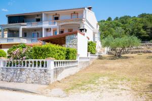 a large white house with a stone fence at Apartments with parking space Mrljane, Pasman - 20056 in Pašman