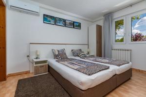 a bedroom with a large bed and two windows at Apartments for families with children Karlovac - 20989 in Karlovac