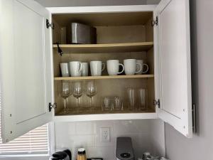 a kitchen cabinet with glasses and wine glasses at Stylish, Relaxing & Comfy 3 BDR Home in Bristol
