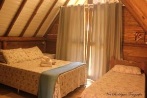 1 dormitorio con 2 camas y ventana en Chalés do Pedro Hospedagem e Restaurante en Praia de Araçatiba
