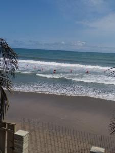 a group of people in the waves in the ocean at KorKoCove Beachfront Suites in Accra +3 photos