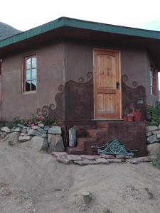een huis met een bank voor een deur bij Aldea Biocultural Ayelen in Piedra Lisa