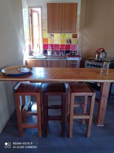 een keuken met een grote houten tafel en krukken bij Aldea Biocultural Ayelen in Piedra Lisa