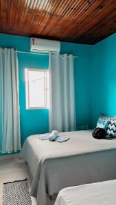 um quarto com uma parede azul, uma cama e uma janela em Cantinho Santiago em Alto Paraíso de Goiás