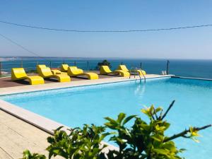 a swimming pool with yellow chairs and the ocean at Colina do Elétrico in Figueira da Foz