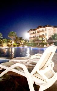 two white lounge chairs sitting next to a pool at night at VG SUN CUMBUCO-Lake Flat C1 201 1 a 4 pessoas in Caucaia