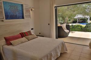a bedroom with a bed and a large sliding glass window at Villa Leonor in Es Calo