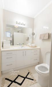 a white bathroom with a sink and a toilet at Dushi Townhouse Curaçao in Willemstad